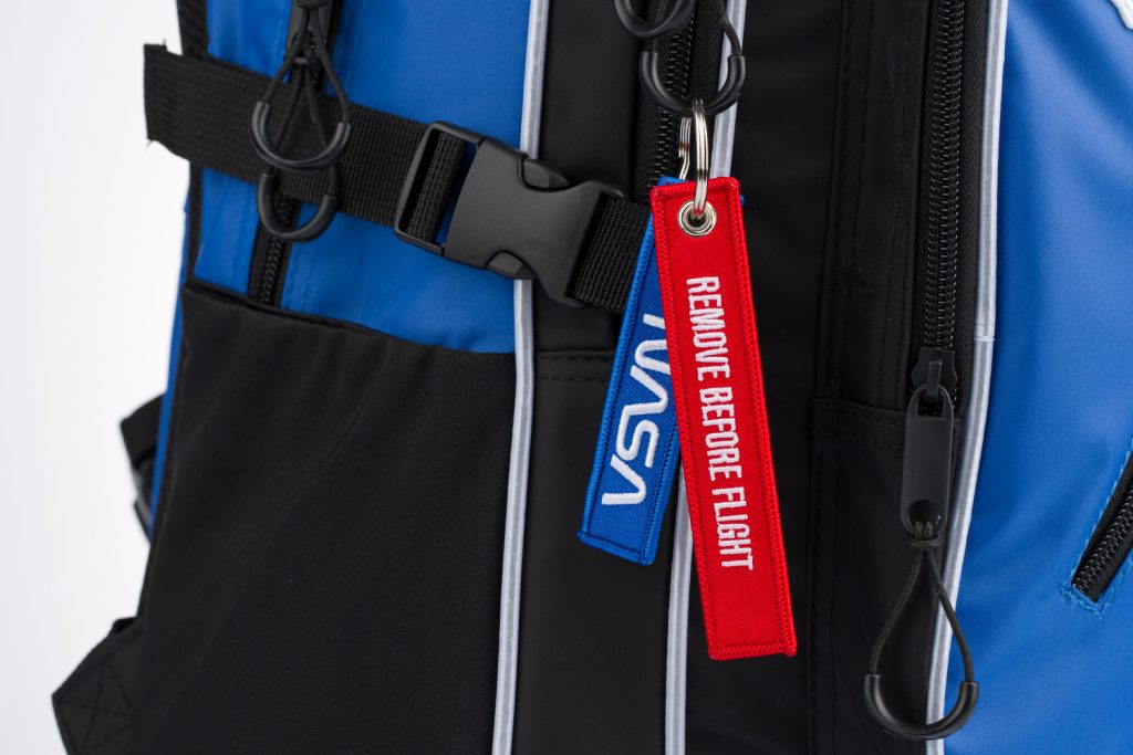 Přívěsky "Remove before flight" na batohu Cubic NASA.